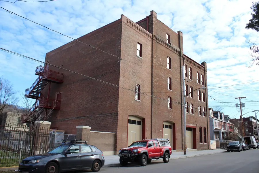 A tall brick building with garage doors and a fire escape in Hazelwood
