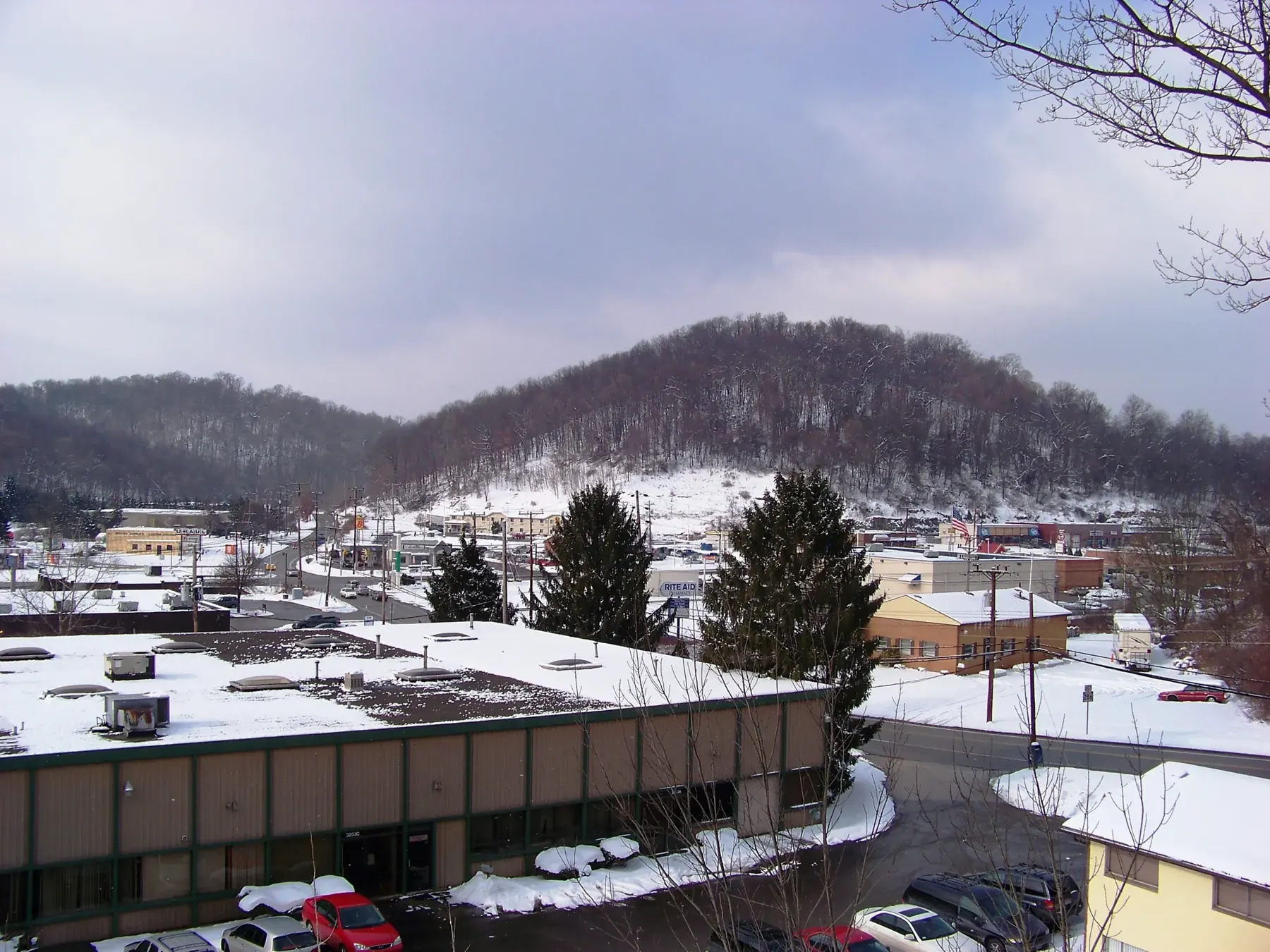 Snow on commercial rooftops and wooded hills in Monroeville