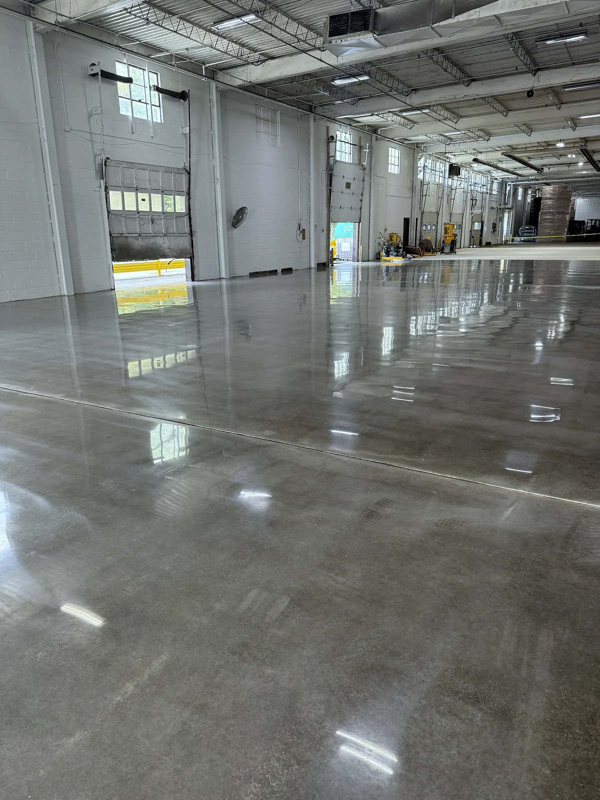 Industrial bay with a raised dock door open to daylight, polished concrete floor with a saw cut joint, Pittsburgh area.