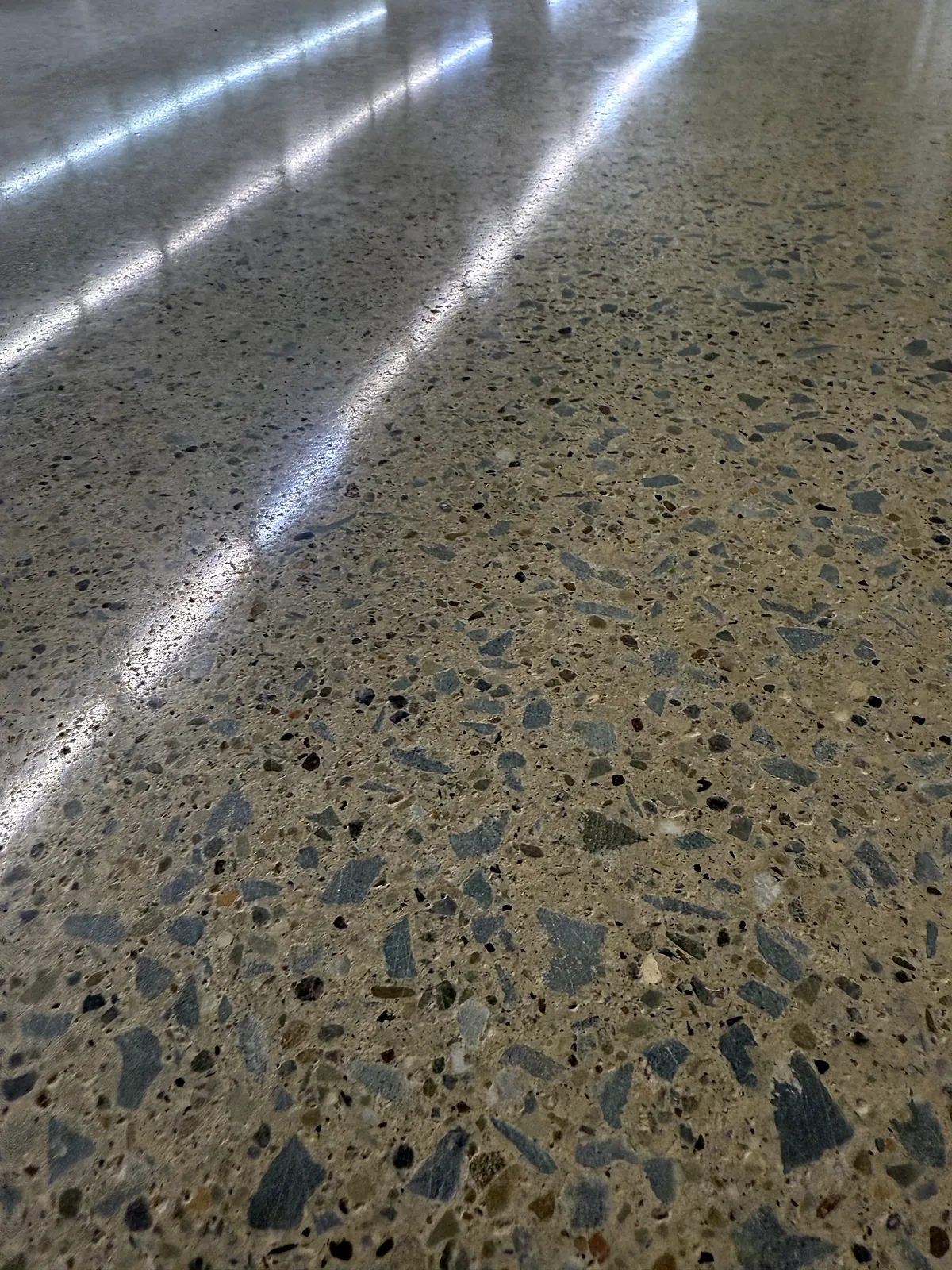 Close view of a polished concrete floor with exposed aggregate and light streaks across the surface, Pittsburgh area.