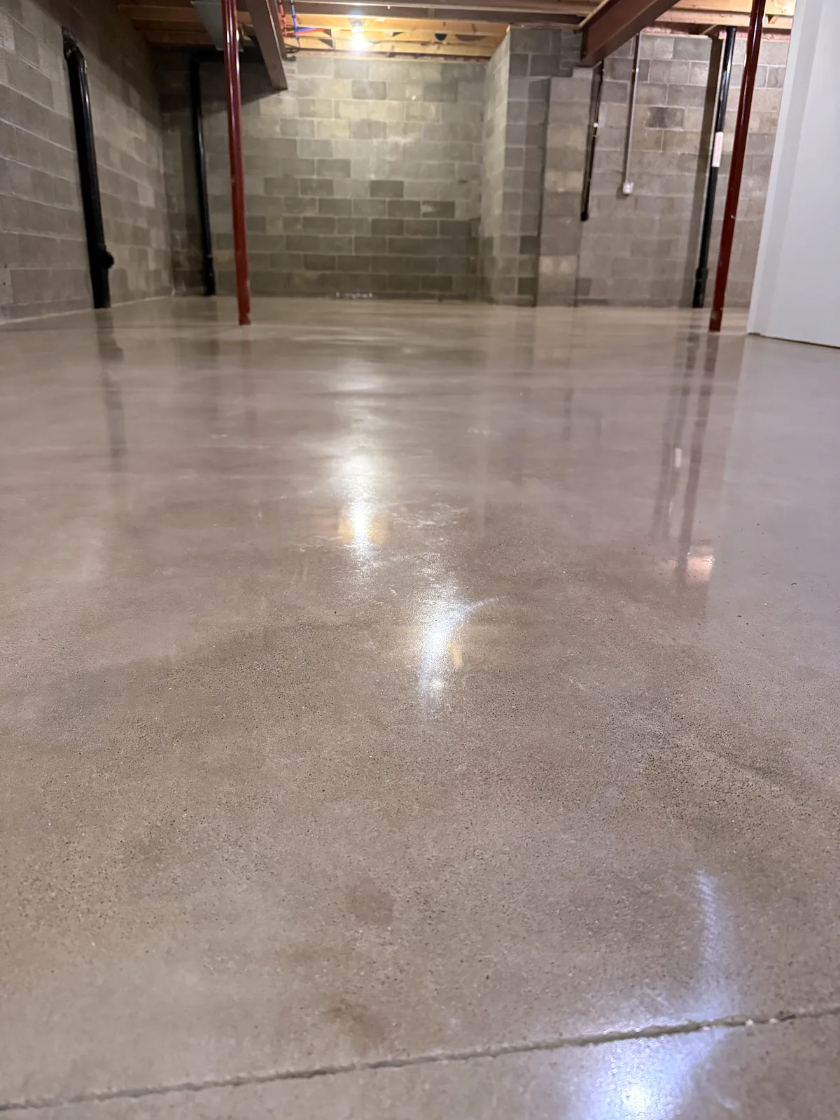 Low view of a polished concrete floor in a room with a block wall, steel beams and a post, Pittsburgh area.