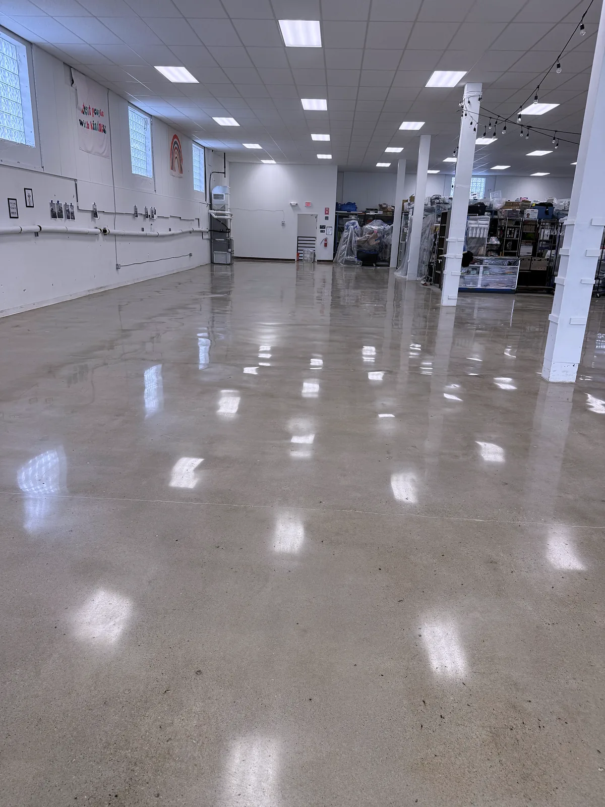 Same open commercial room from the left, polished concrete floor, shelving and displays at the far end, Pittsburgh area.