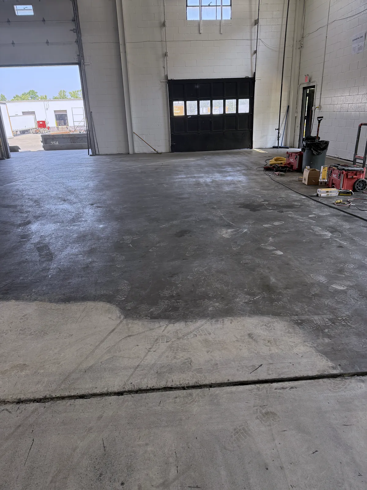Warehouse floor part way through grinding, the lighter ground area meeting the darker untreated slab, Pittsburgh area.